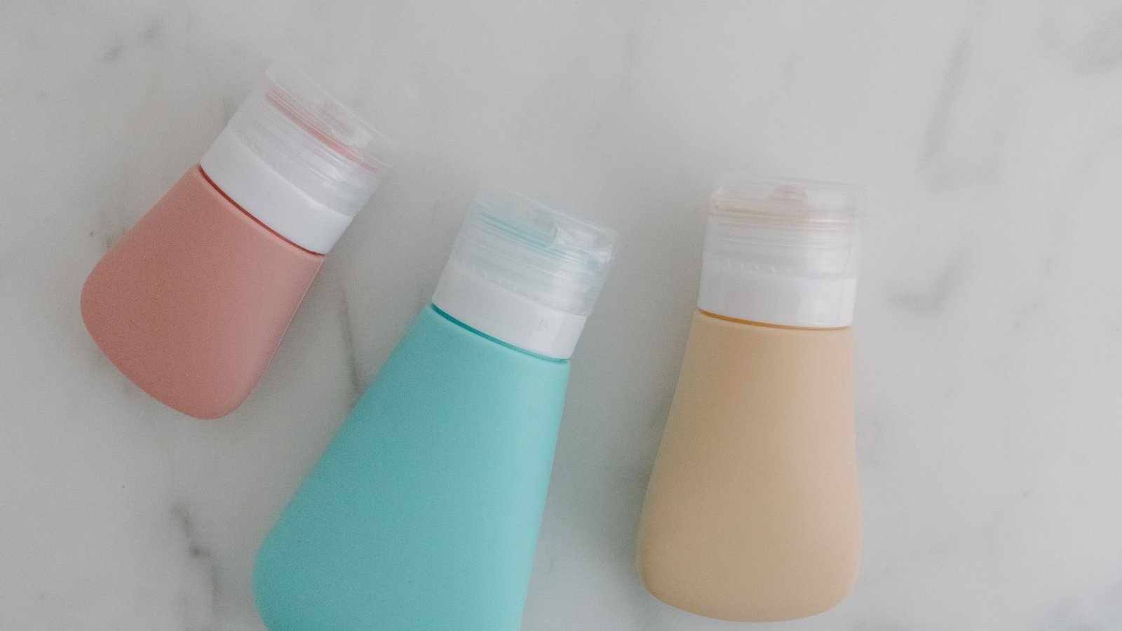 Petits flacons de voyage alignés sur une surface blanche, format 100 ml pour avion