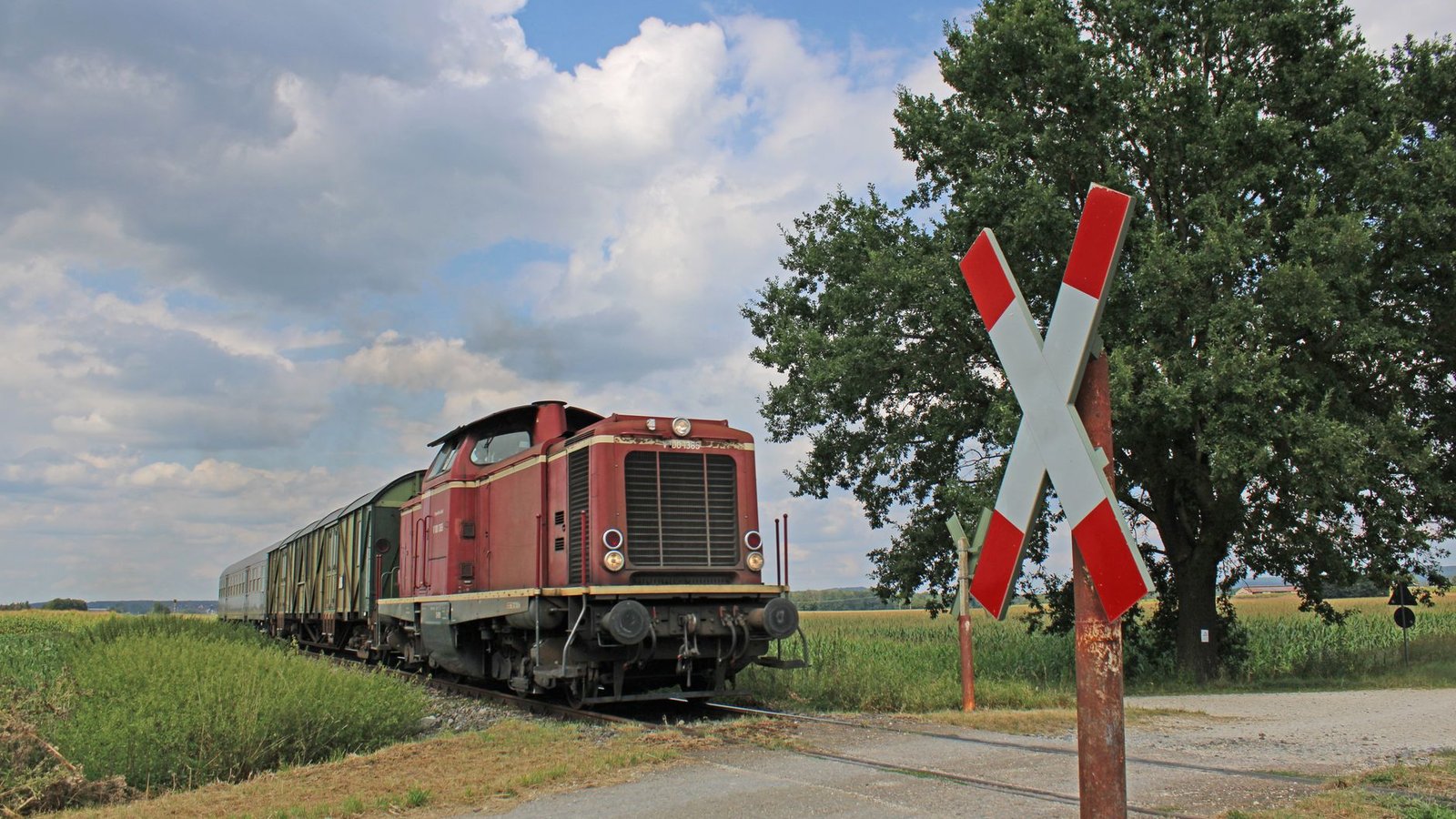 Train de marchandises franchissant un passage à niveau sur une voie ferrée rurale