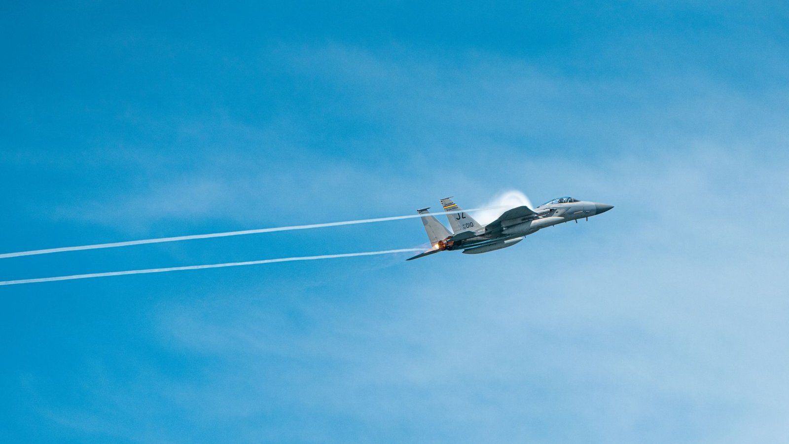 Avion militaire traversant le mur du son avec un cône de vapeur visible