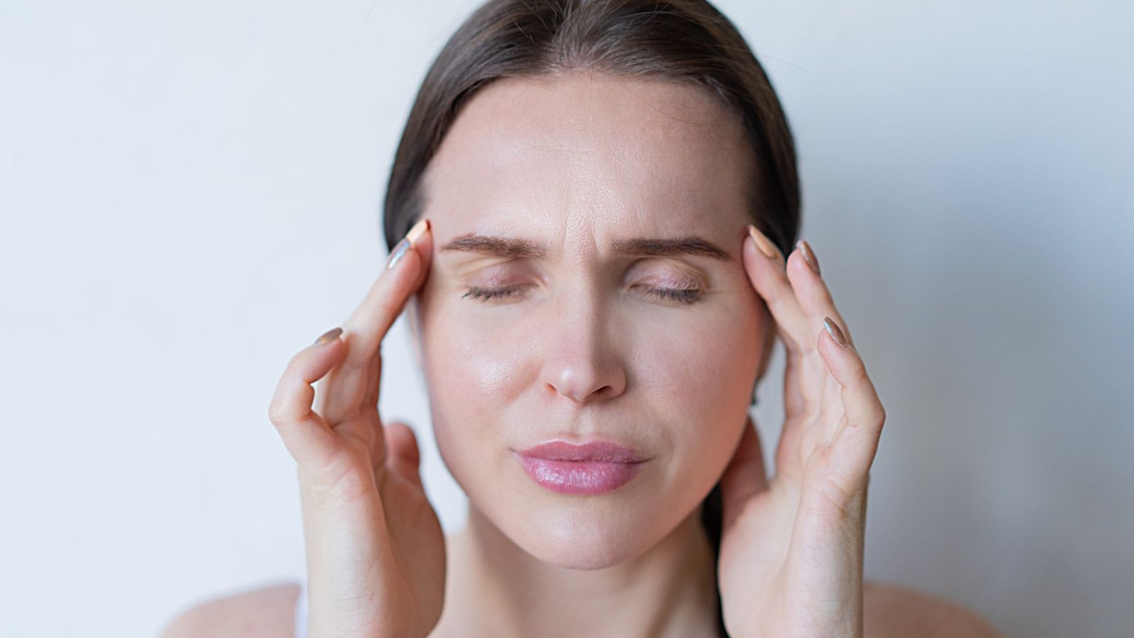 Personne se tenant l'oreille, exprimant une gêne auditive