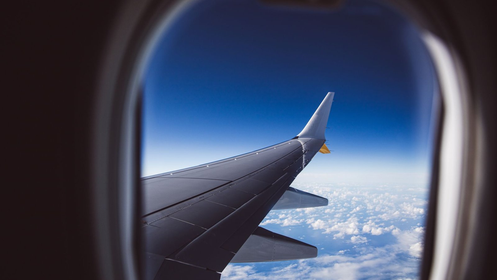 Vue depuis un hublot d'avion en vol, ciel bleu et aile visible